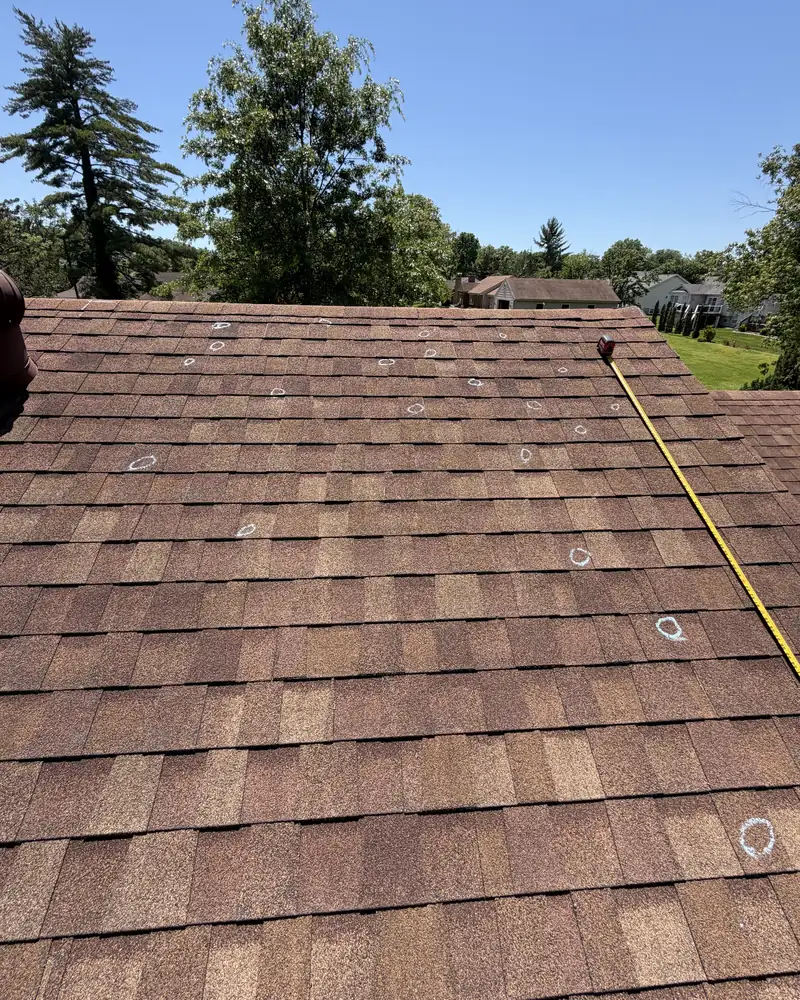 Inspector’s chalk marks on an asphalt shingle roof with a measuring tape along the slope